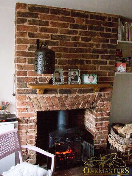 A small brick fireplace with an oak mantle shelf and corbels