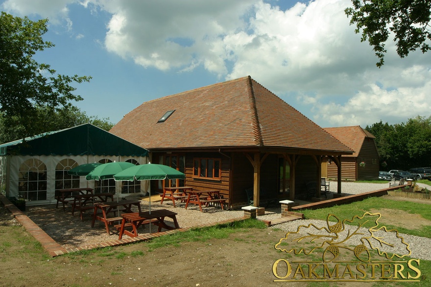 Oak clad leisure building with roof extension over oak columns to create shade