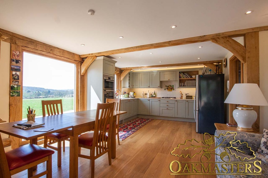 Inside rural retirement home showing hand finished oak beams and curved braces framing kitchen area 