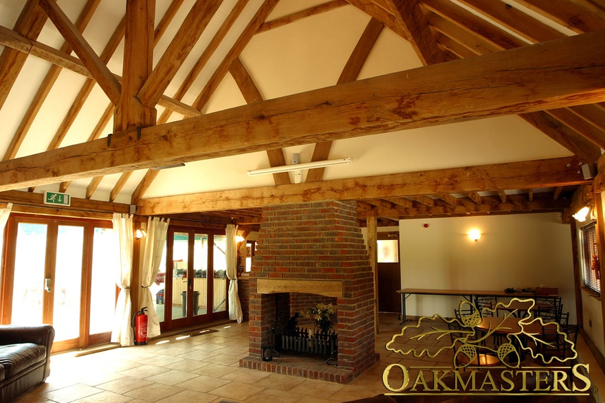 Bespoke oak trusses and rafters above central brick fireplace in corporate entertainment suite