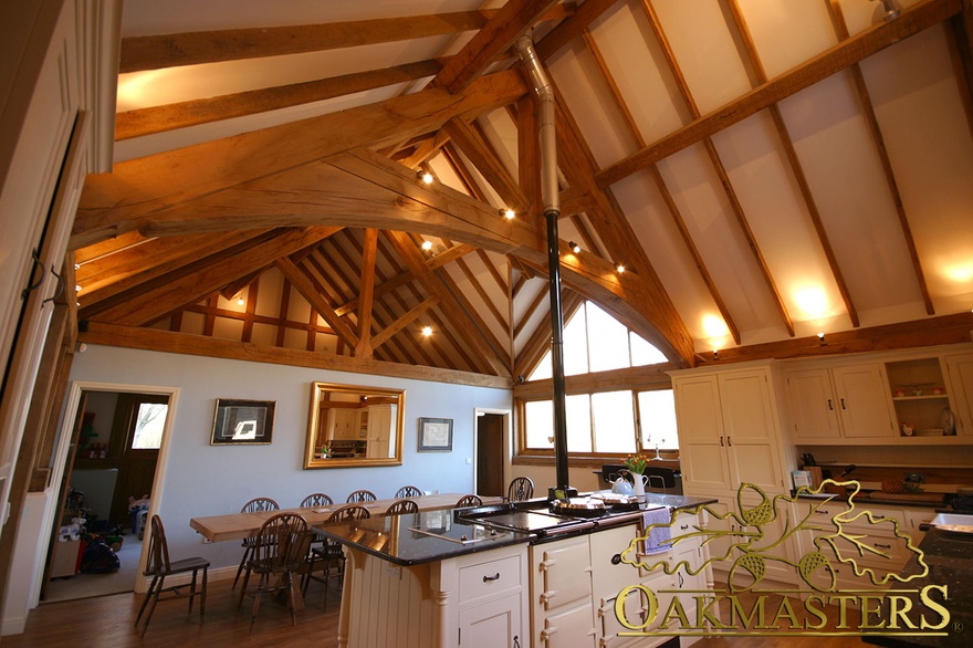 Vaulted ceiling with exposed oak trusses and rafters adds height to large kitchen and dining area