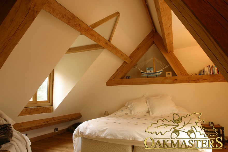 Exposed oak ceiling beams create decorative storage in loft bedroom of country home