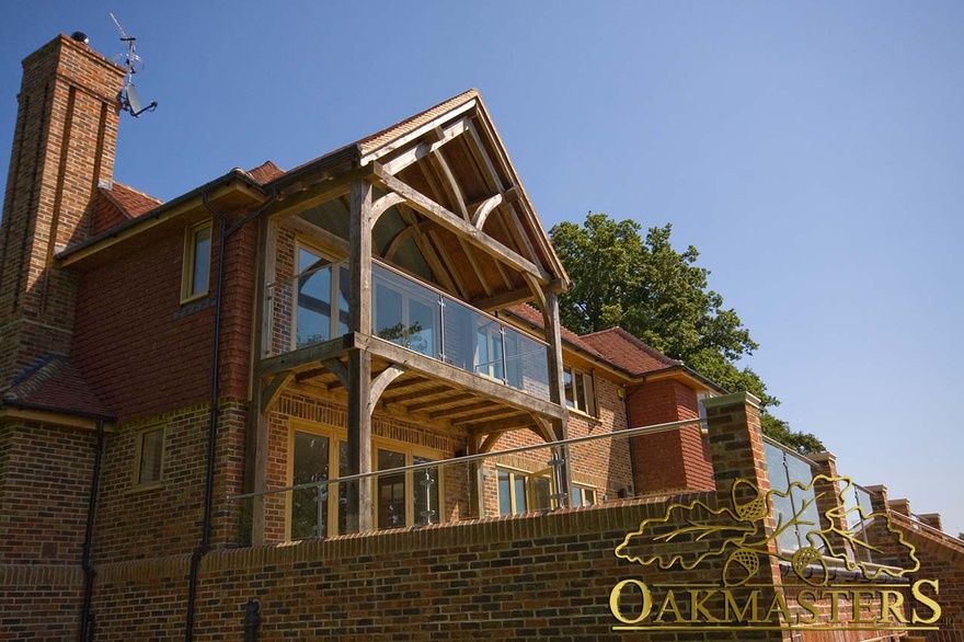 Contemporary glazed balcony supported by oak braces on modern family property