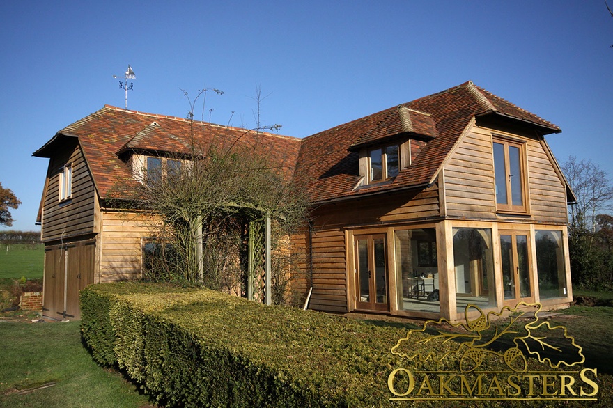Oak clad L-shaped country house with double oak door garage and partial glazing