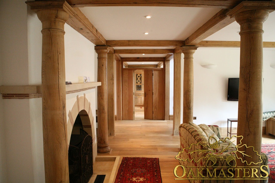 Hand crafted round oak columns line walk way through sitting room of unusual country house