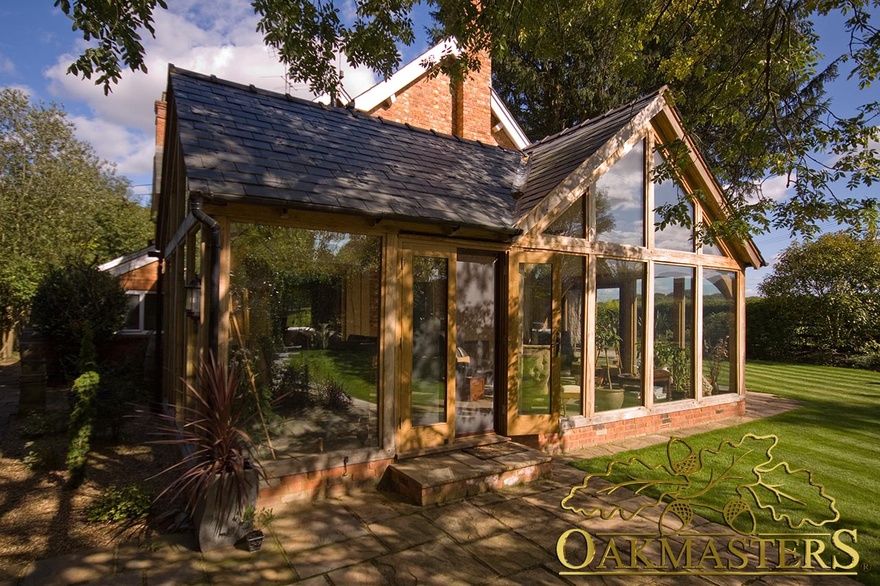 Oak frame dual aspect garden room with glazed gable built to match cottage
