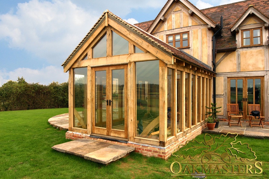 Exterior glazed gable and oak frame doors leading out of garden room built to match house
