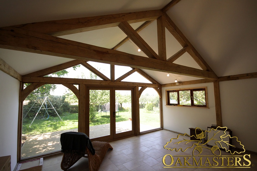 Oak-frame king post truss and full height glazing in garden room and garage complex