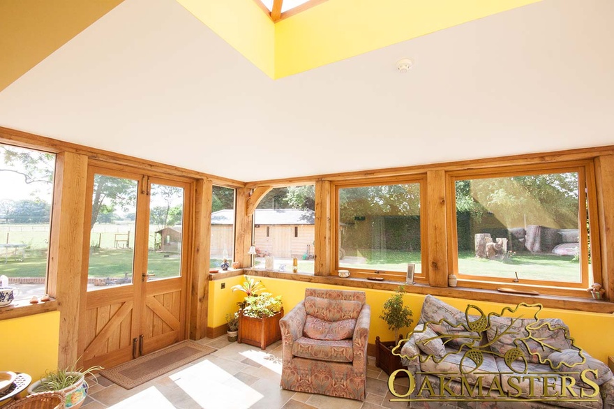 Light filled sun room with oak frame part glazed walls and door to garden