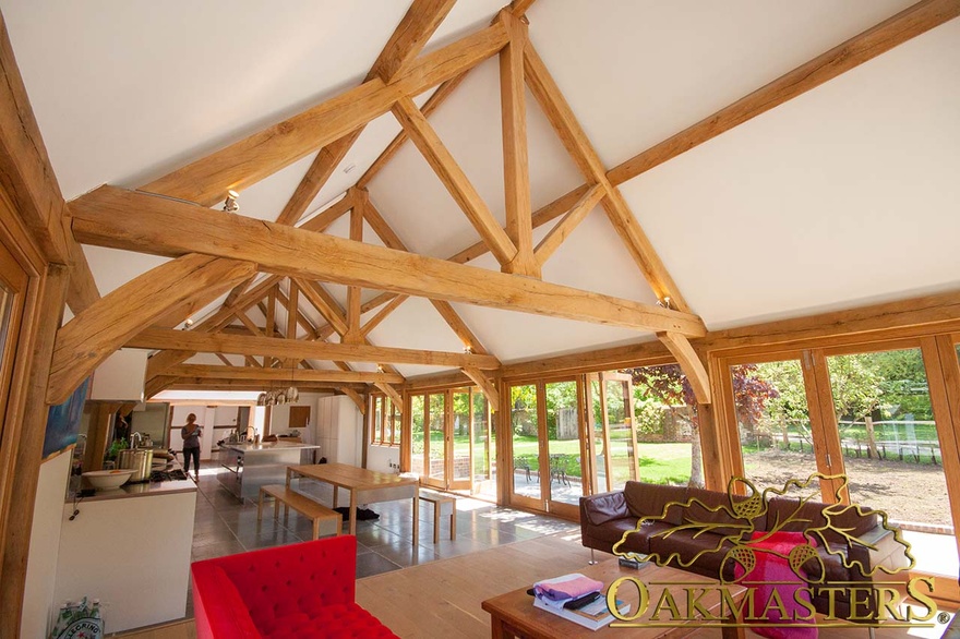 Open ceiling with exposed oak trusses maximises space and light in modern gardenroom kitchen