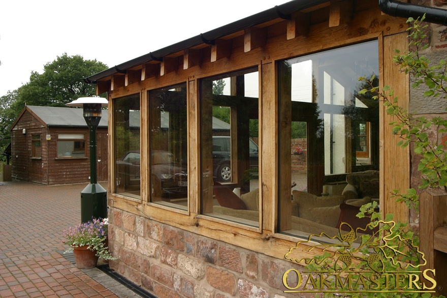 Detail of bespoke oakframe windows and roof rafter tails on oak and stone sun-room