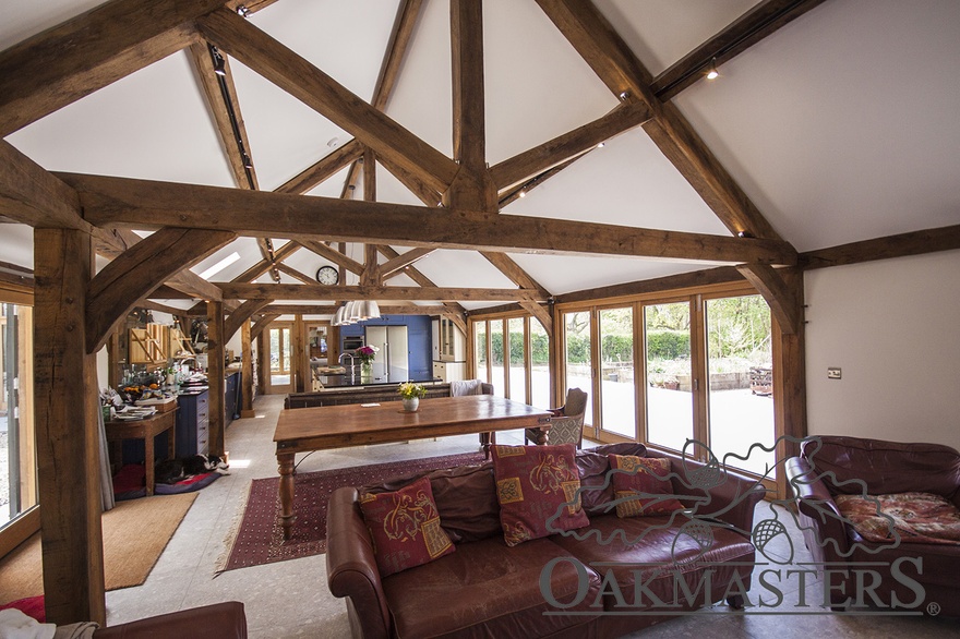 Family living space in an open plan kitchen diner with oak king post trusses and exposed oak purlins