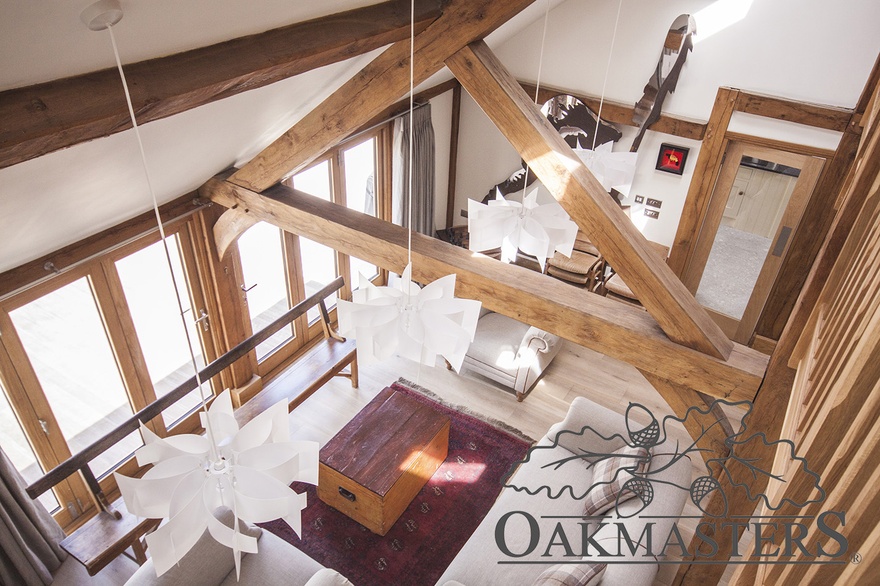 View down from the landing into the lounge area through a large oak king post truss