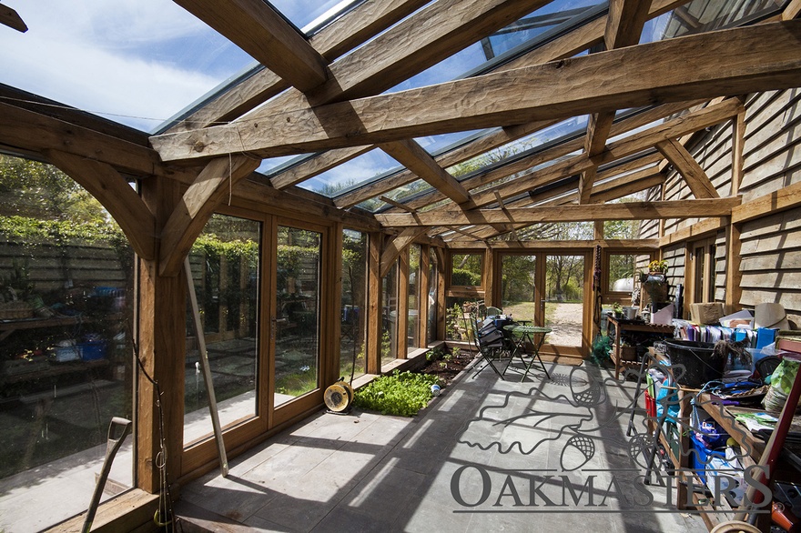 The oak greenhouse features half trusses and a glazed roof
