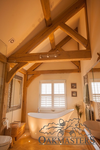 Upstairs in the oak extension, the en-suite bathroom features beautiful structural beams and exposed oak trusses