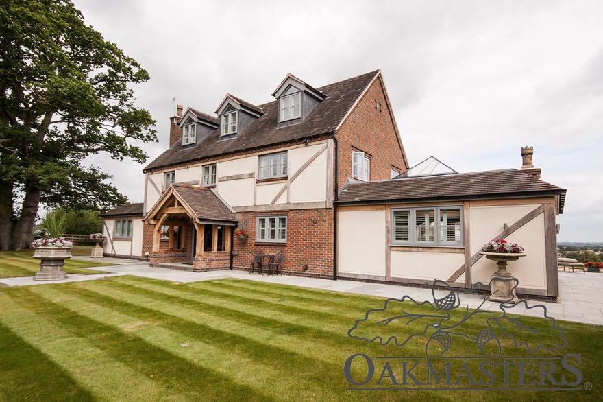 The oak clad house with an oak framed extension either side looks pretty and symmetrical