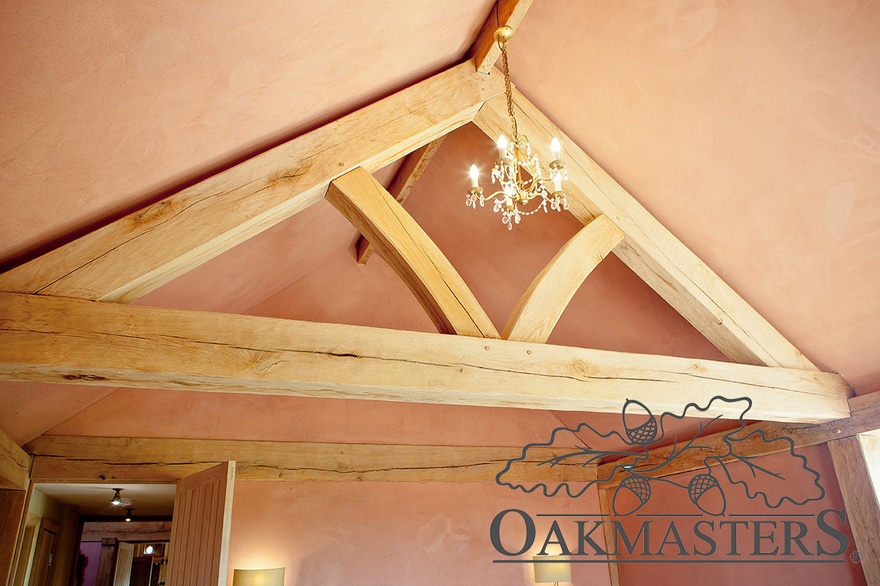 A floating queen post oak truss has been installed in a country barn bedroom to create an illusion of a vaulted ceiling