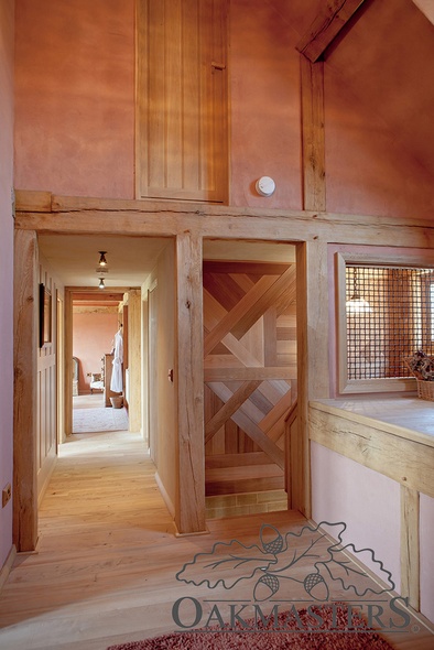 The staircase opens up onto an oak frame landing, decorated with coloured render in earthy tones