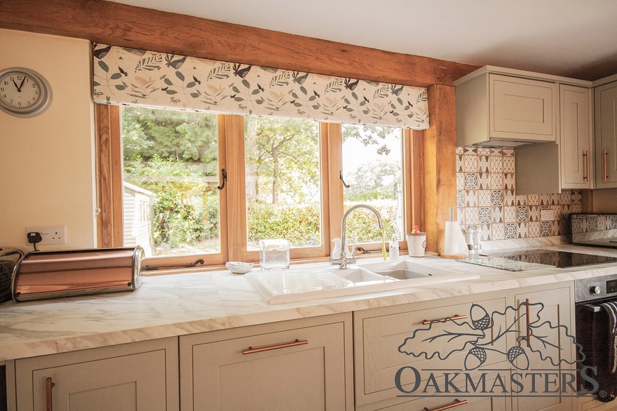 The kitchen windows are inset in the green oak structural frame.