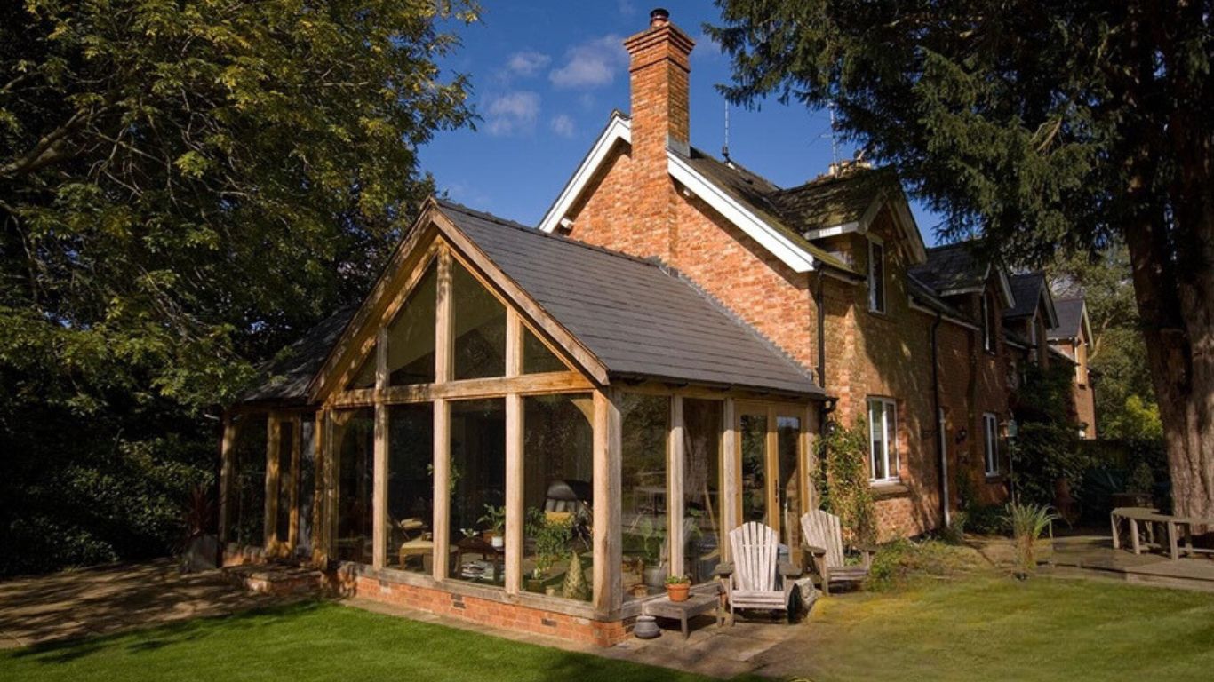 An oak garden room with a pitched roof design blends the outdoor garden with the indoor living space.