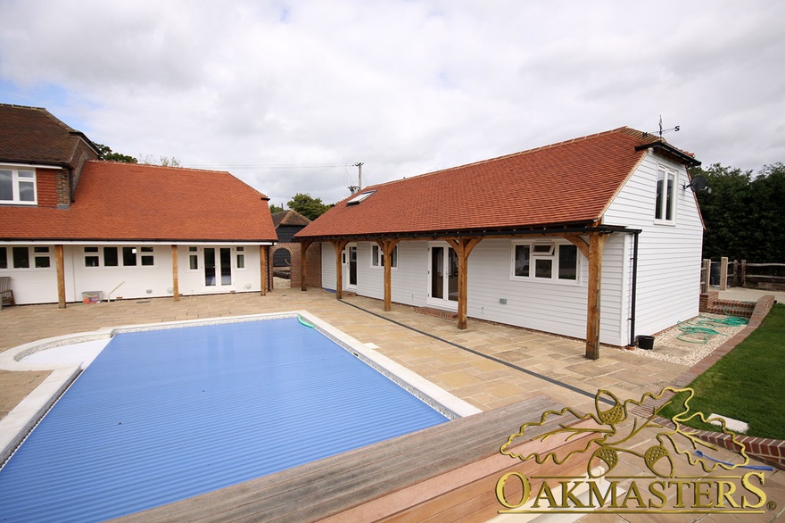 Painted timber clad buildings surrounding outdoor pool in private leisure complex