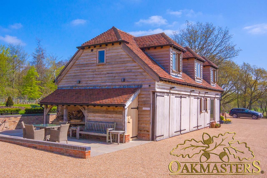 Lockable shed and open log store to end of oak-clad retirement house