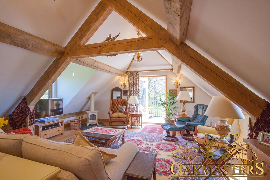 Cosy roof sitting room in retirement property with exposed oak trusses and dormer windows adding extra space and natural light