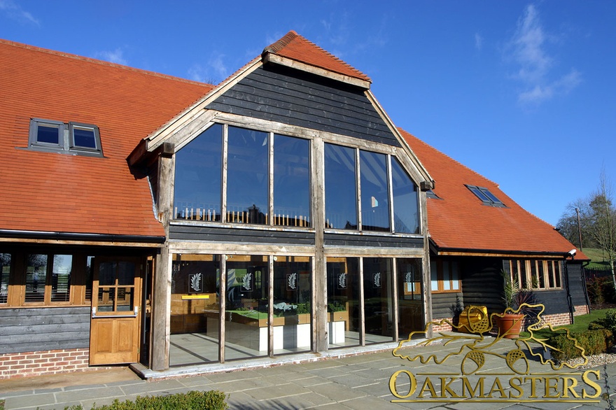 Double height oakframed glazing under timber clad hip roof