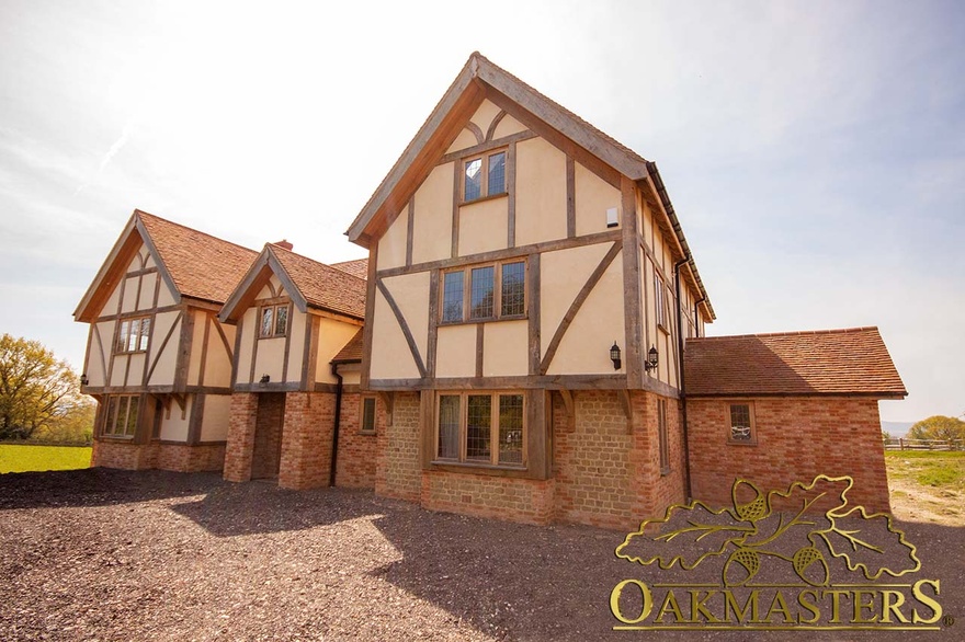 Front exterior of large oak framed house with glazed gables