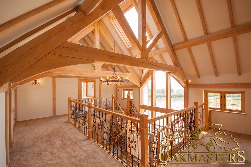 Oak truss and ceiling rafters surround oak frame velux window above oak and wrought iron balustrade