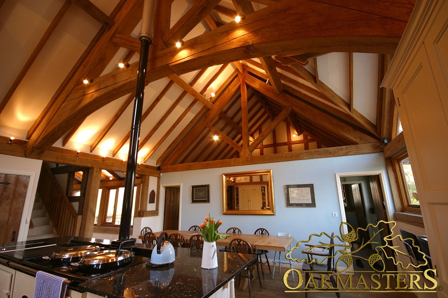 Spot lighting showcases open ceiling with exposed rafters and kingpost truss above kitchen