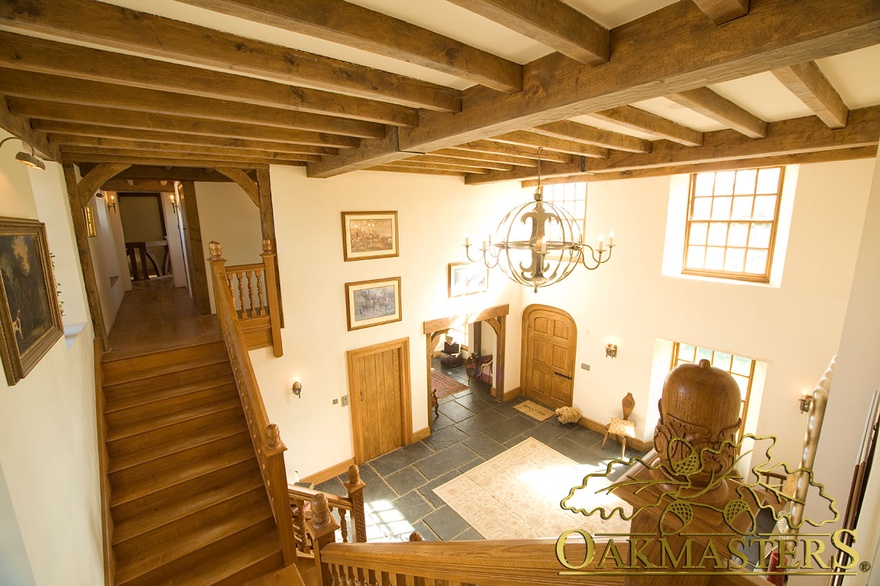 Double height entrance hall with exposed beams in Isle of Man manx oak and stone house