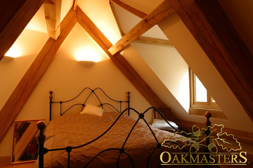 Bed framed by oak roof truss in modern country extension