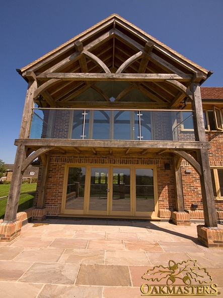 Exposed king post truss above oak-frame balcony on modern house