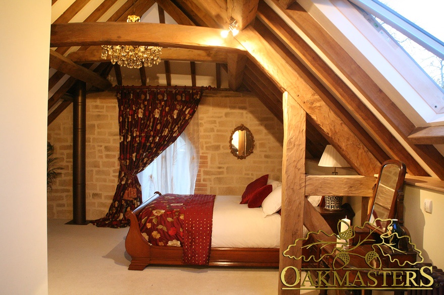 Loft bedroom with exposed queen post oak truss and ceiling beams on Restoration Man TV project