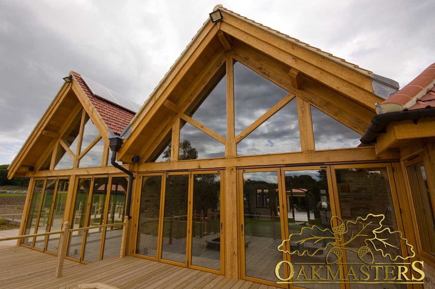 Glazed gable and exposed oak frame glazed doors leading to wood decking patio area