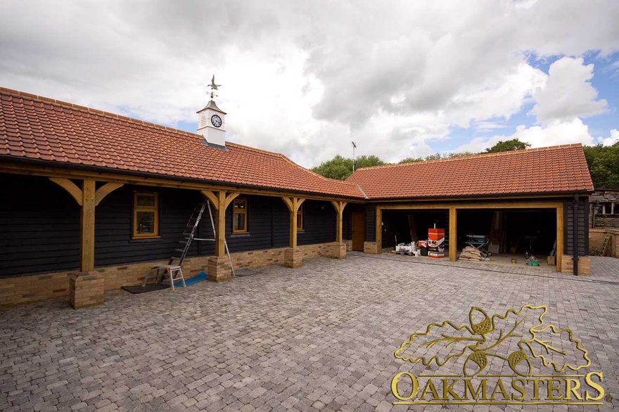 Oak framed double garage bay and oak clad walls with extended roof supported with oak columns and curved braces