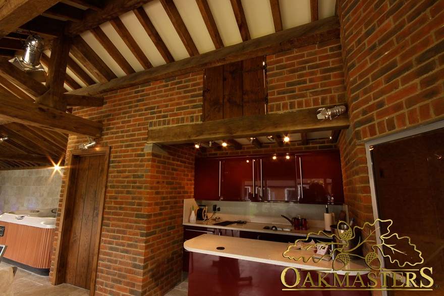 Exposed oak lintel supports kitchen wall in oak and stone pool house and gym