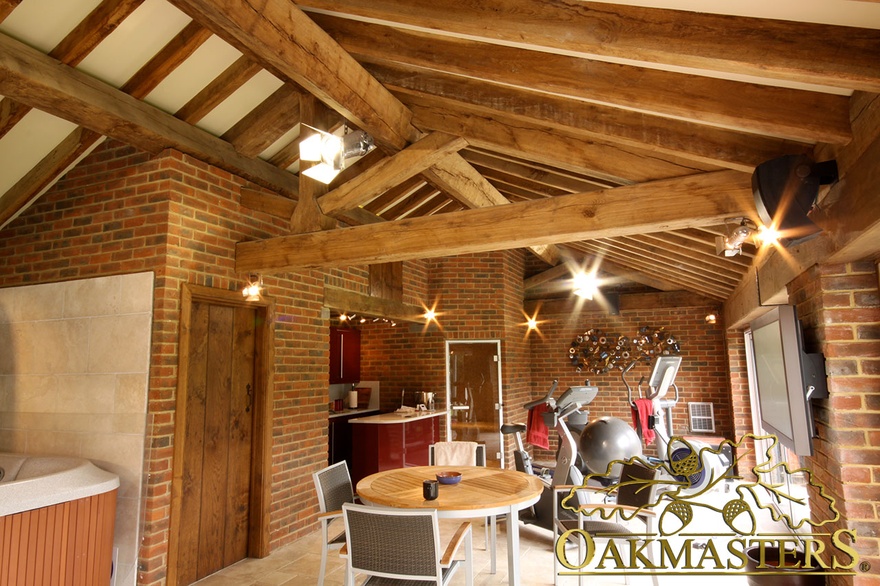 Exposed truss and rafters above relaxation area in oak and stone pool house and gym