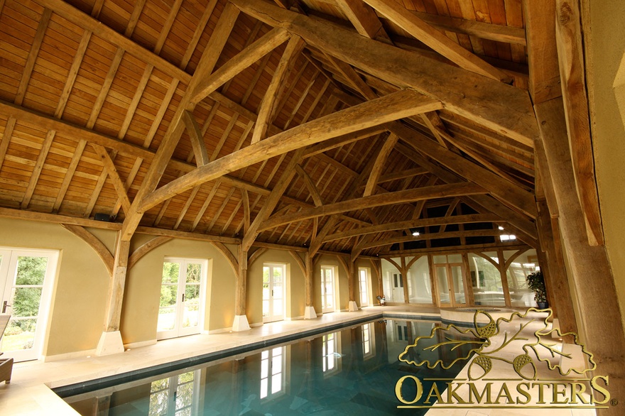 Exposed oak columns support large exposed wooden roof in pool house