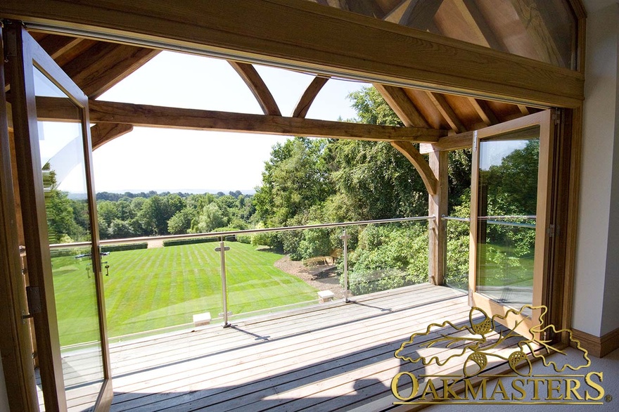 Exposed oak truss and oak frame bi fold doors frame garden balcony views