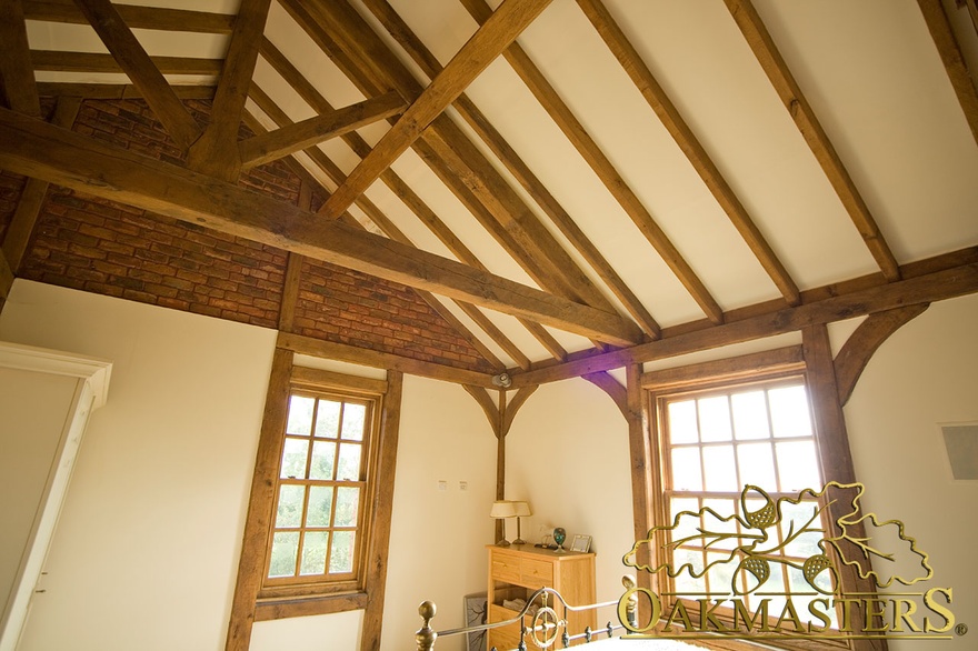 Vaulted ceiling and truss above oakframe windows in country bedroom