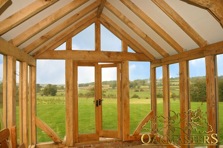 Interior of full height glazing and glazed gable end in garden room built to match existing house