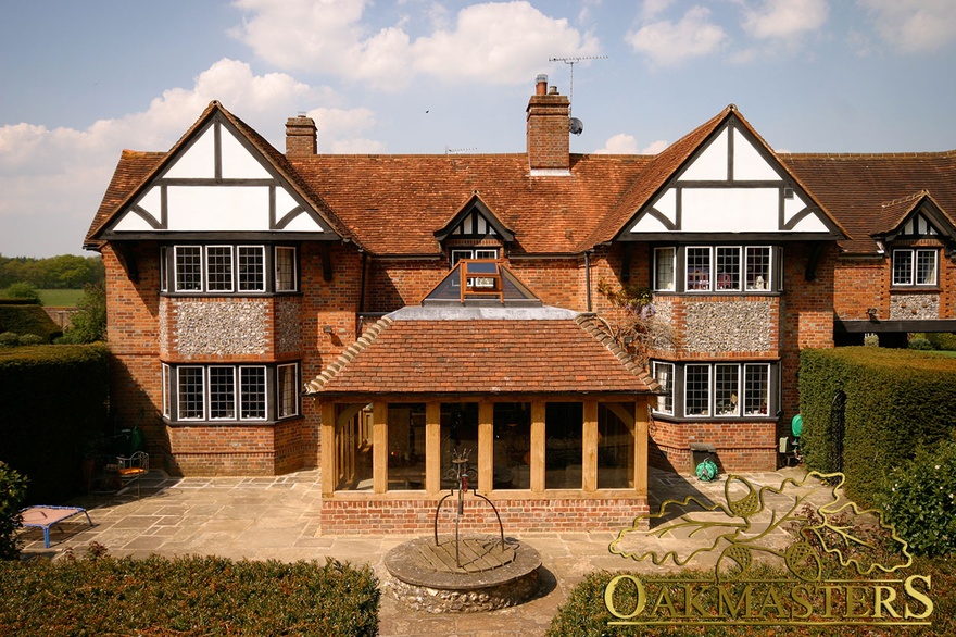 Rear exterior showing orangery integrated with existing brick manor house and glass lantern roof