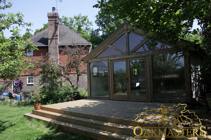 Glazed gable and full height windows lead to wooden patio on garden room and garage complex