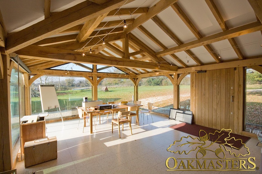 Interior of garden room office with exposed oak vaulted ceilings and full height glazed windows to maximise light and views