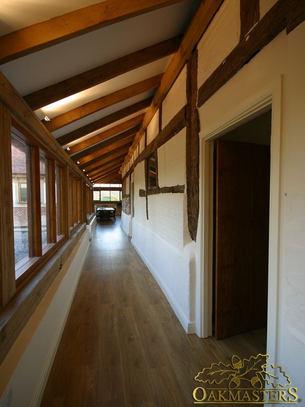 Oak frame and exposed rafters in glazed verandah used as hallway in listed house