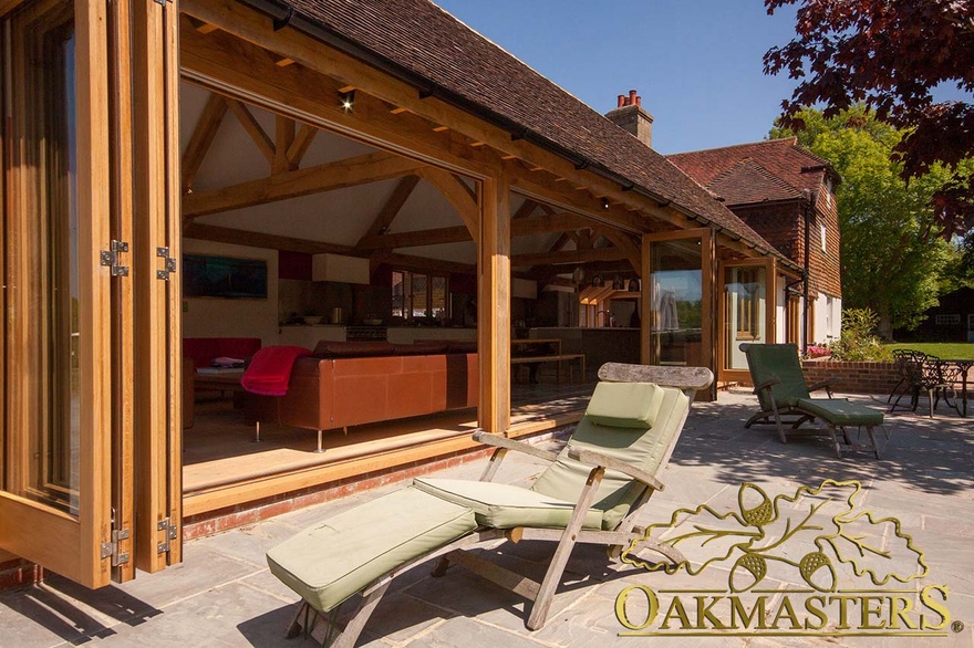 Fully glazed bi fold doors open to transform modern garden room and kitchen 