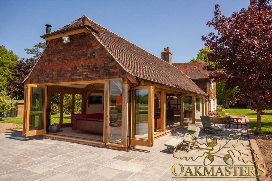 Exterior of modern garden room kitchen with open glazed bi-fold patio doors 