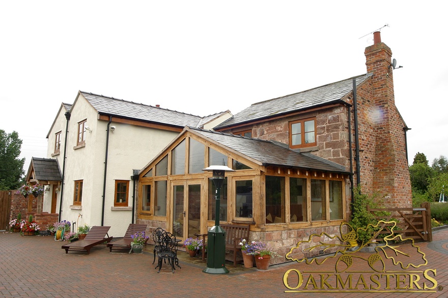 Exterior of glazed gable sun-room and part glazed and stone walls